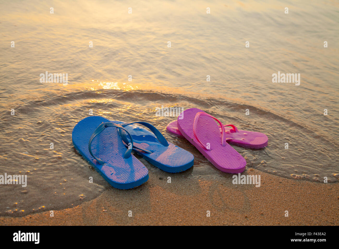 Romantica spiaggia scena. Maschio e femmina flpp flip sandali sulla spiaggia Foto Stock