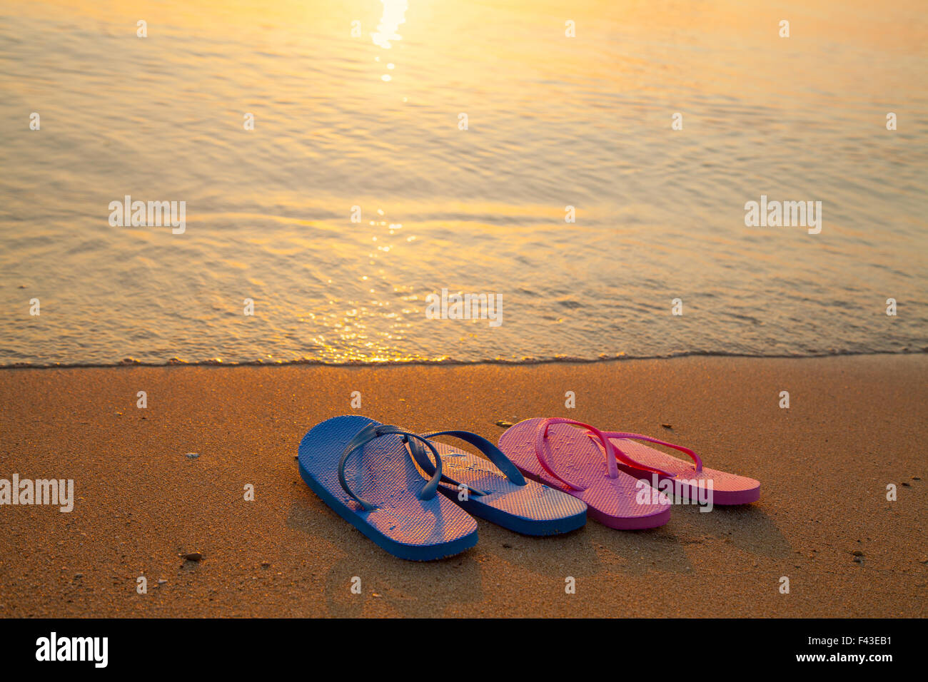 Romantica spiaggia scena. Maschio e femmina flpp flip sandali sulla spiaggia Foto Stock