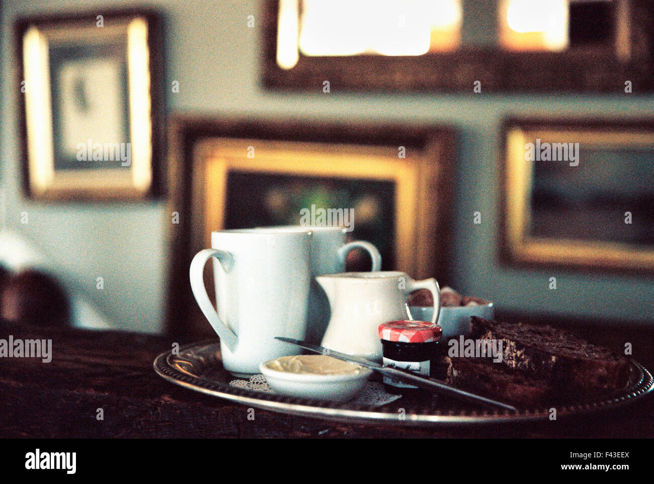 Un edificio storico della fine del XVIII secolo, interno, ora un hotel ed un ristorante. Un vassoio tè su un tavolo in una stanza piena di immagini. Foto Stock