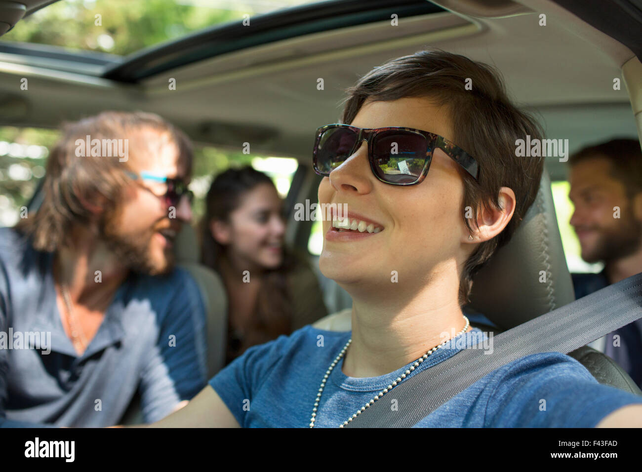 Un gruppo di persone all'interno di un automobile in un viaggio su strada. Vista verso il sedile posteriore di quattro passeggeri. Foto Stock