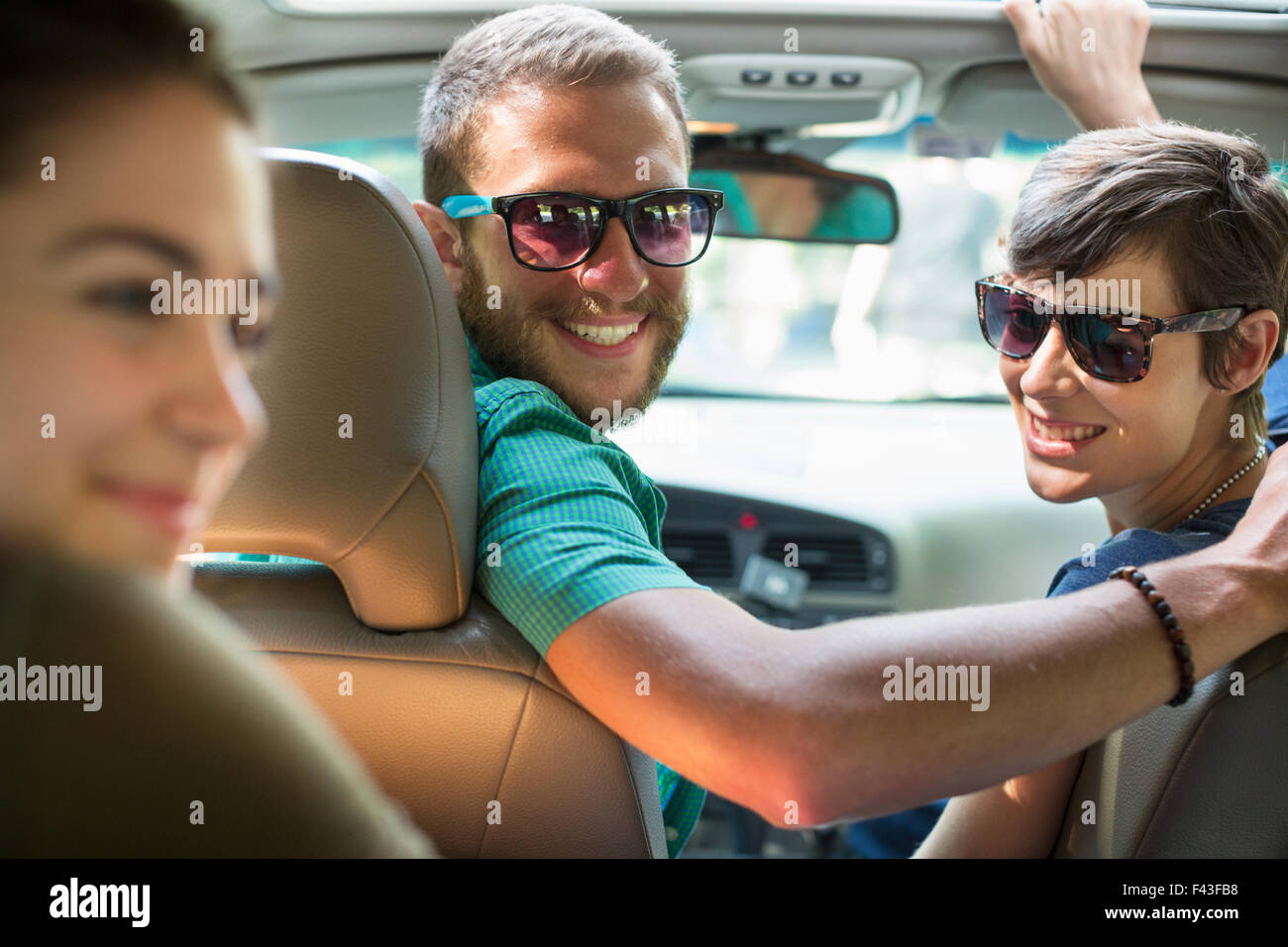 Un gruppo di persone all'interno di un automobile in un viaggio su strada. Vista dal sedile posteriore. Foto Stock