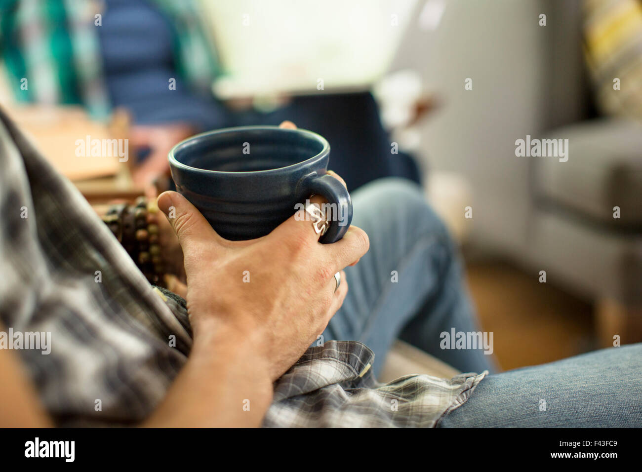 Una persona che tiene un grande nero china mug seduto in una sedia. Foto Stock