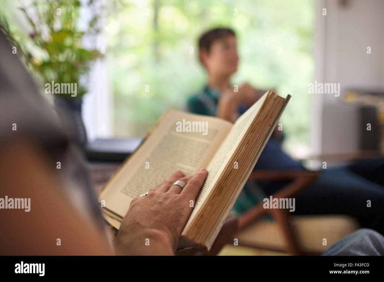 Una persona seduta a leggere un libro. Foto Stock