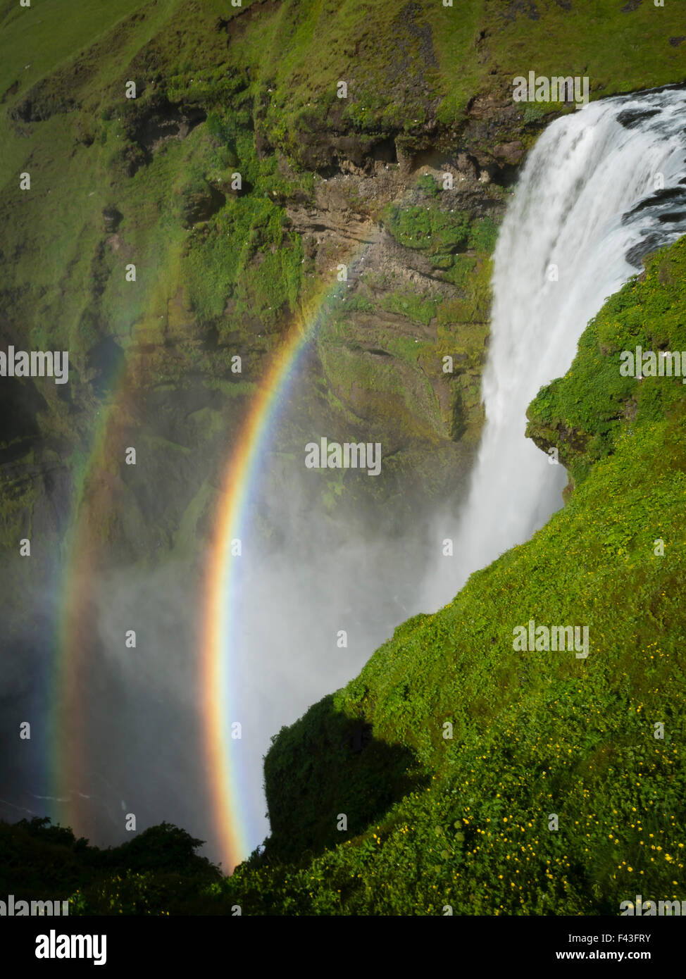 Skogafoss cascata con un doppio arcobaleno nella nebbia e vapore che sale dall'acqua. Foto Stock