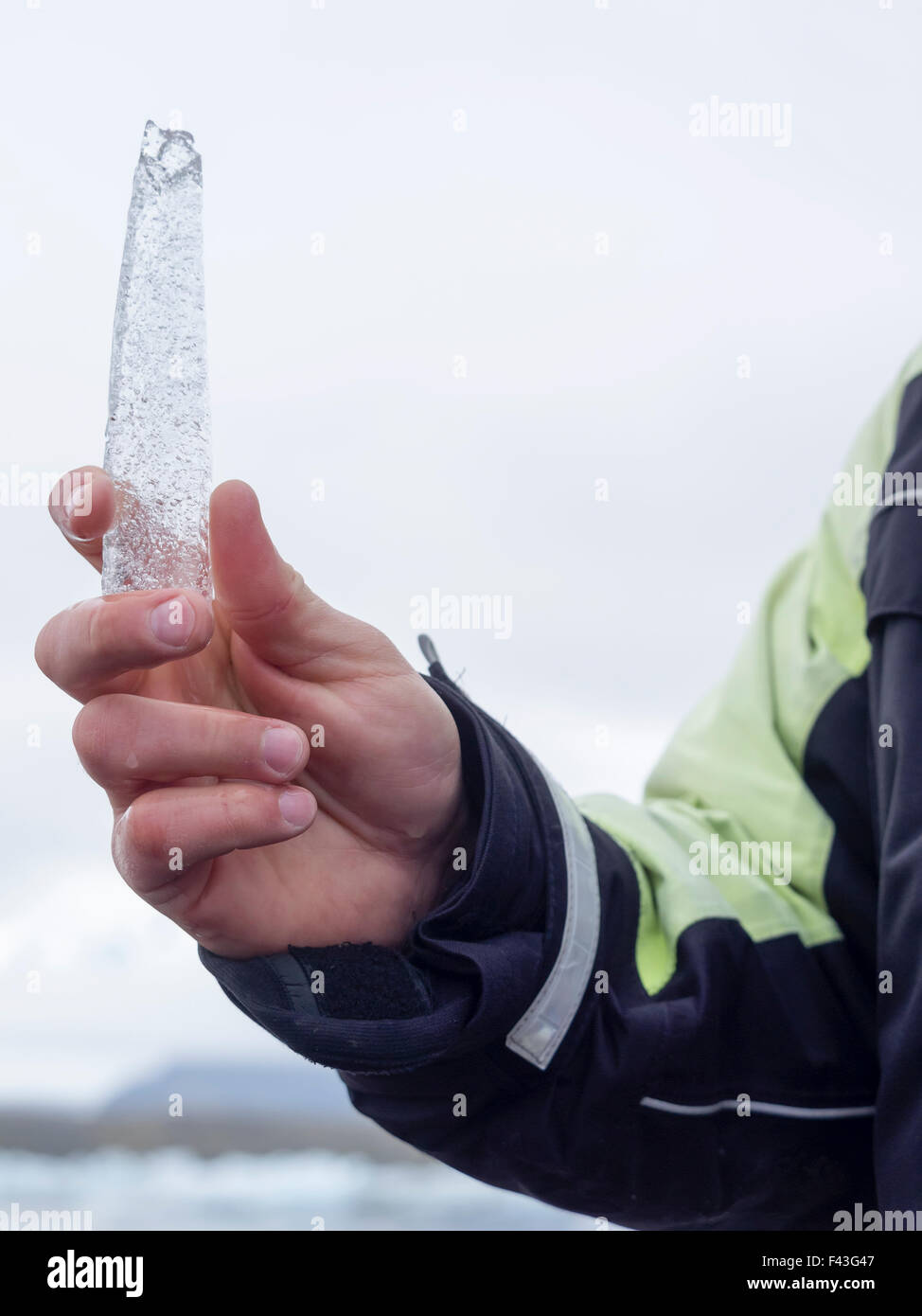 Una guida di trattenimento di un nucleo di ghiaccio campione dalla laguna glaciale nella sua mano. Foto Stock
