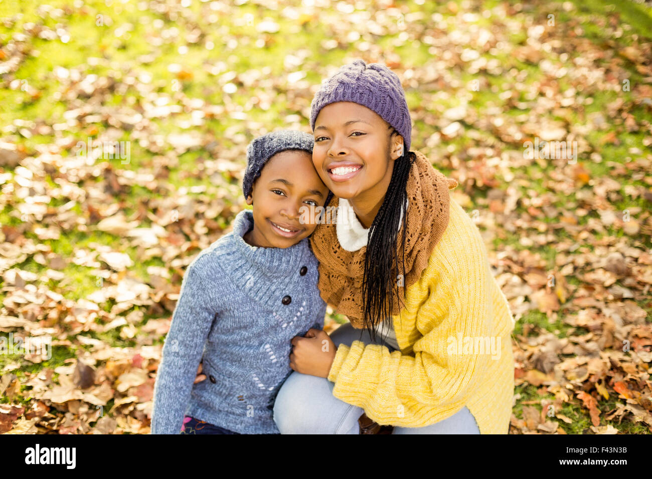 Giovane madre con sua figlia seduta in foglie Foto Stock