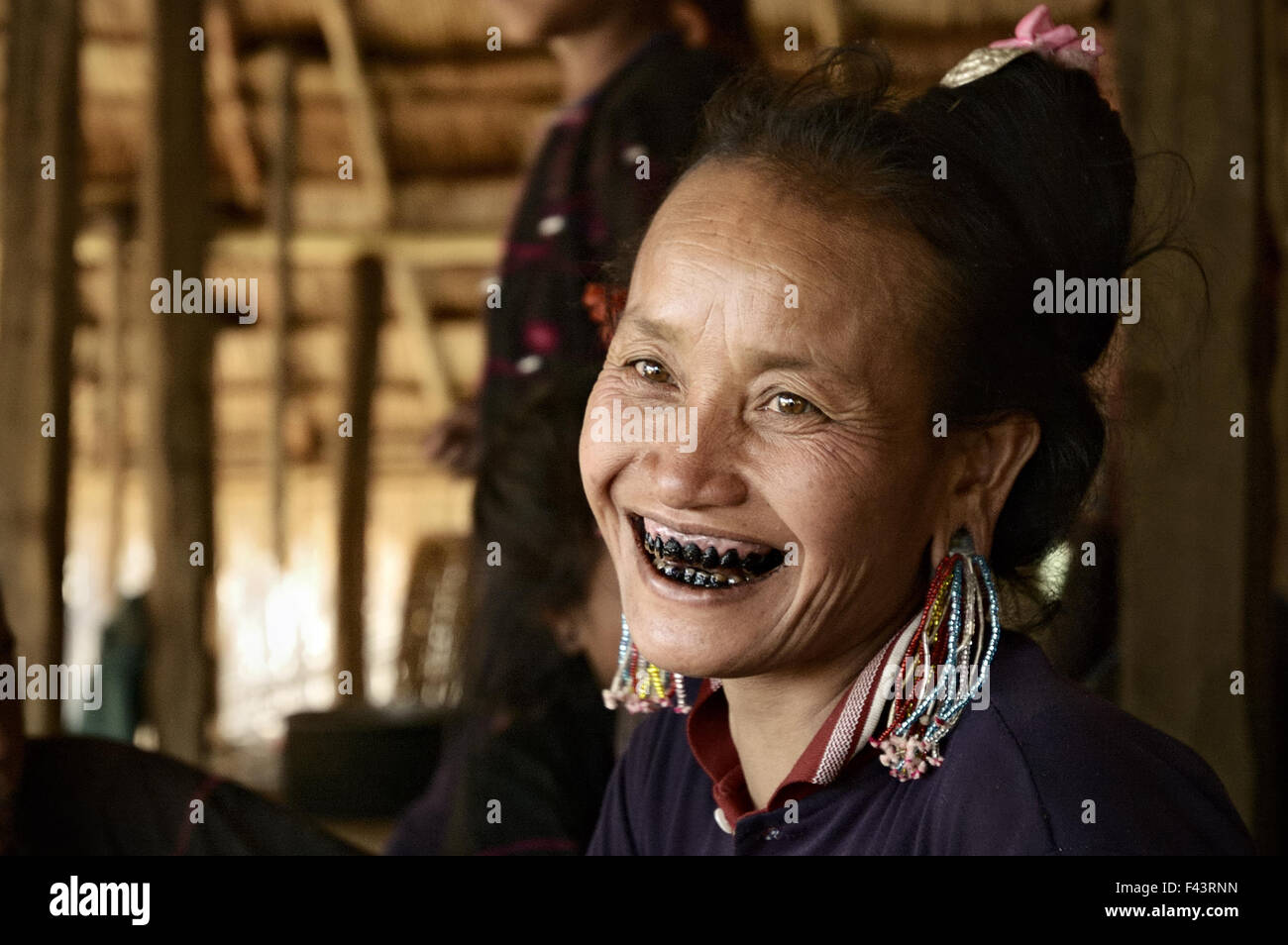 Donna di Ann tribù con denti nero sorrisi dentro casa sua in un villaggio intorno a Kengtung, Stato Shan, Myanmar Foto Stock