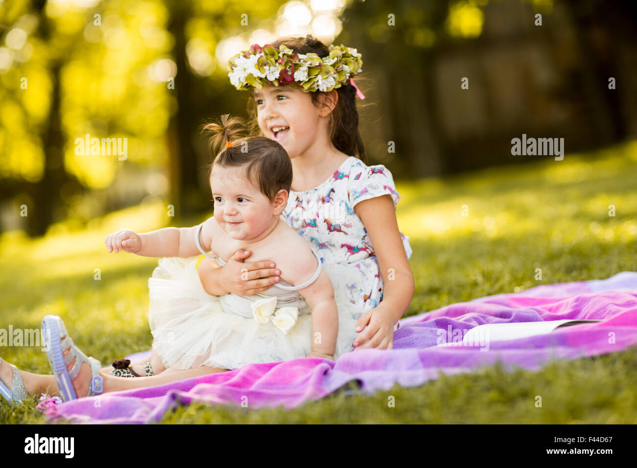 Bambina e baby sitting in erba Foto Stock