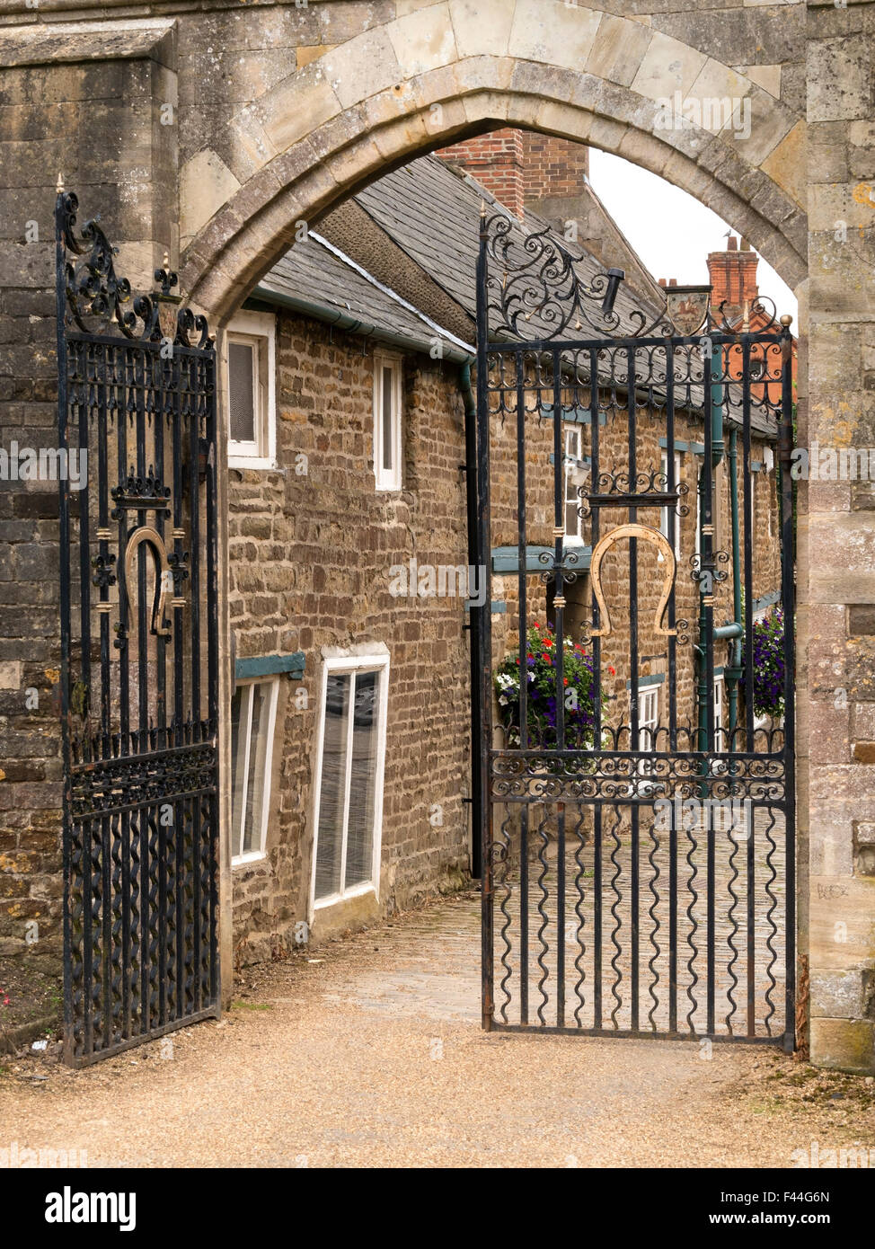 Arco in pietra e cancelli in ferro battuto all'ingresso i motivi della grande hall del castello di Oakham, Oakham, Rutland, England, Regno Unito Foto Stock