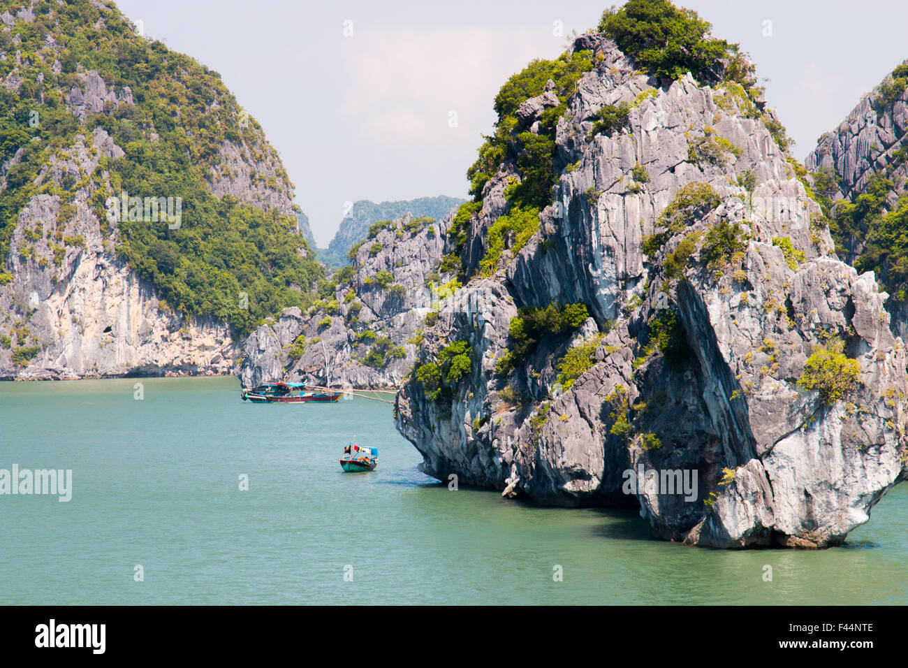 Barche da pesca tra antiche isole calcaree nella baia di Bai tu Long, parte della baia di ha Long, patrimonio mondiale dell'UNESCO, Vietnam, Asia Foto Stock