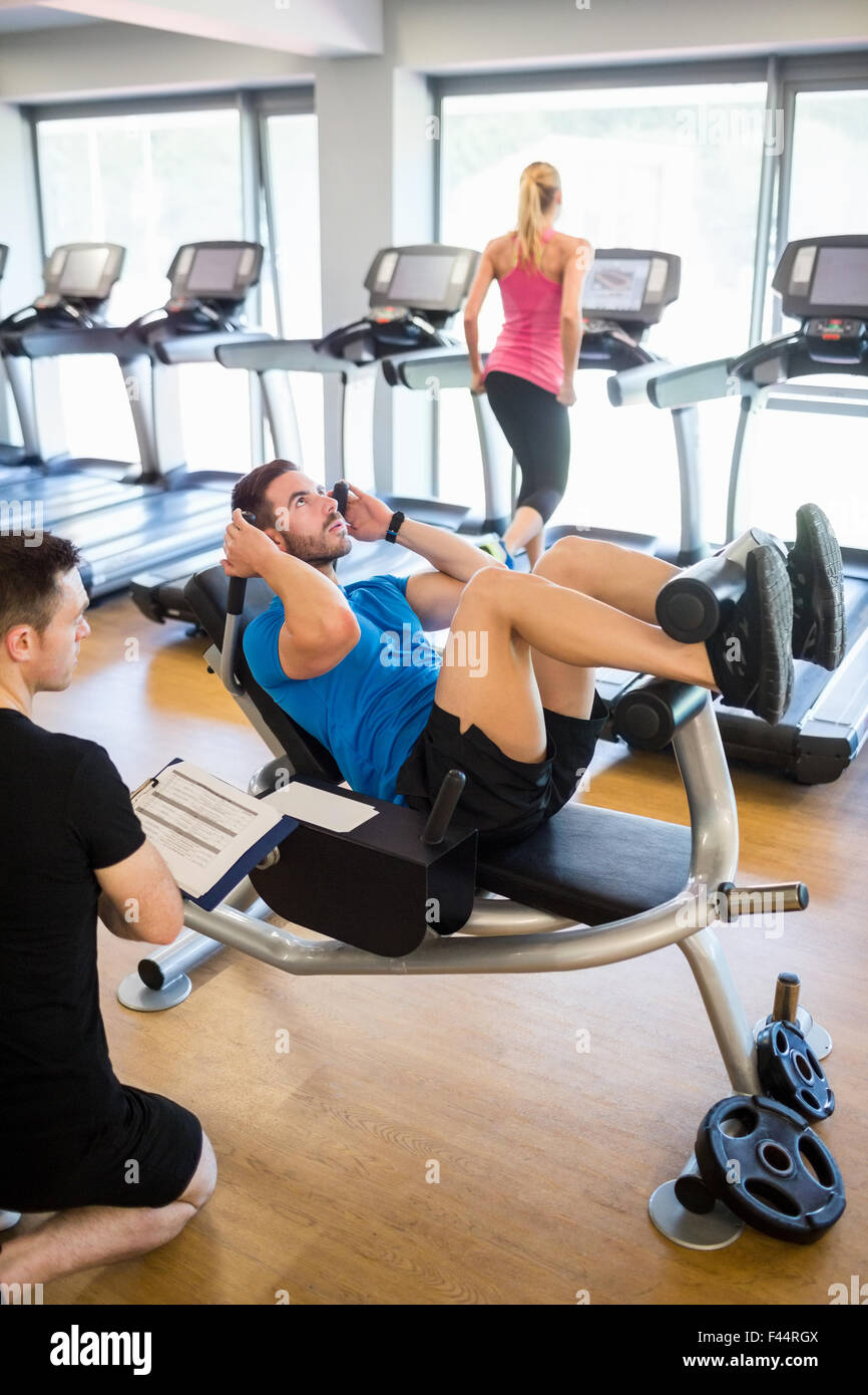 Montare l'uomo facendo sit ups con trainer Foto Stock