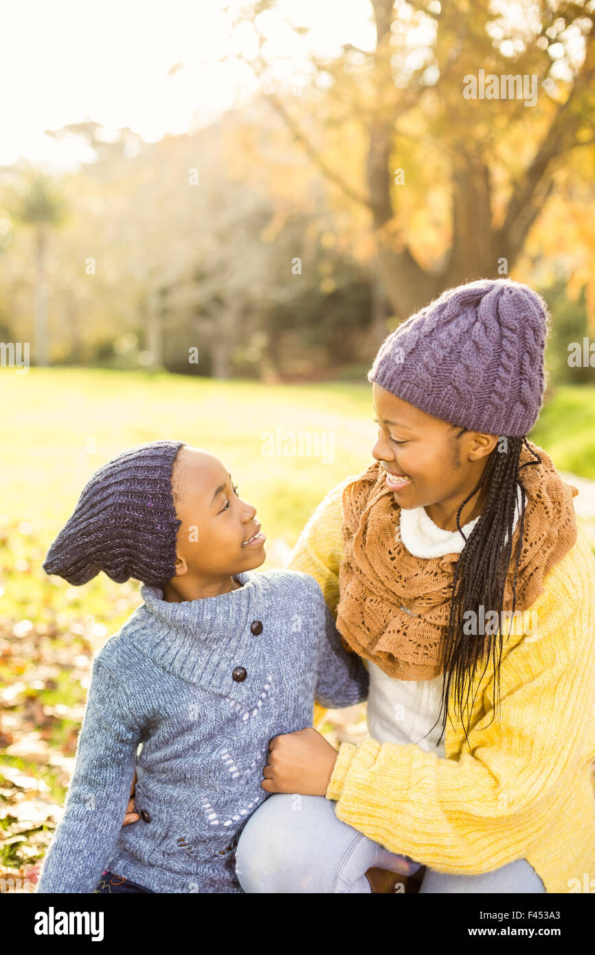 Giovane madre con sua figlia seduta in foglie Foto Stock