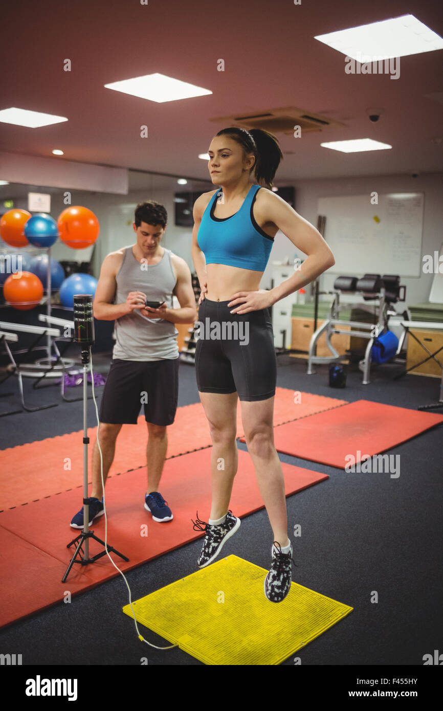 Montare donna misurando il suo salto con trainer Foto Stock