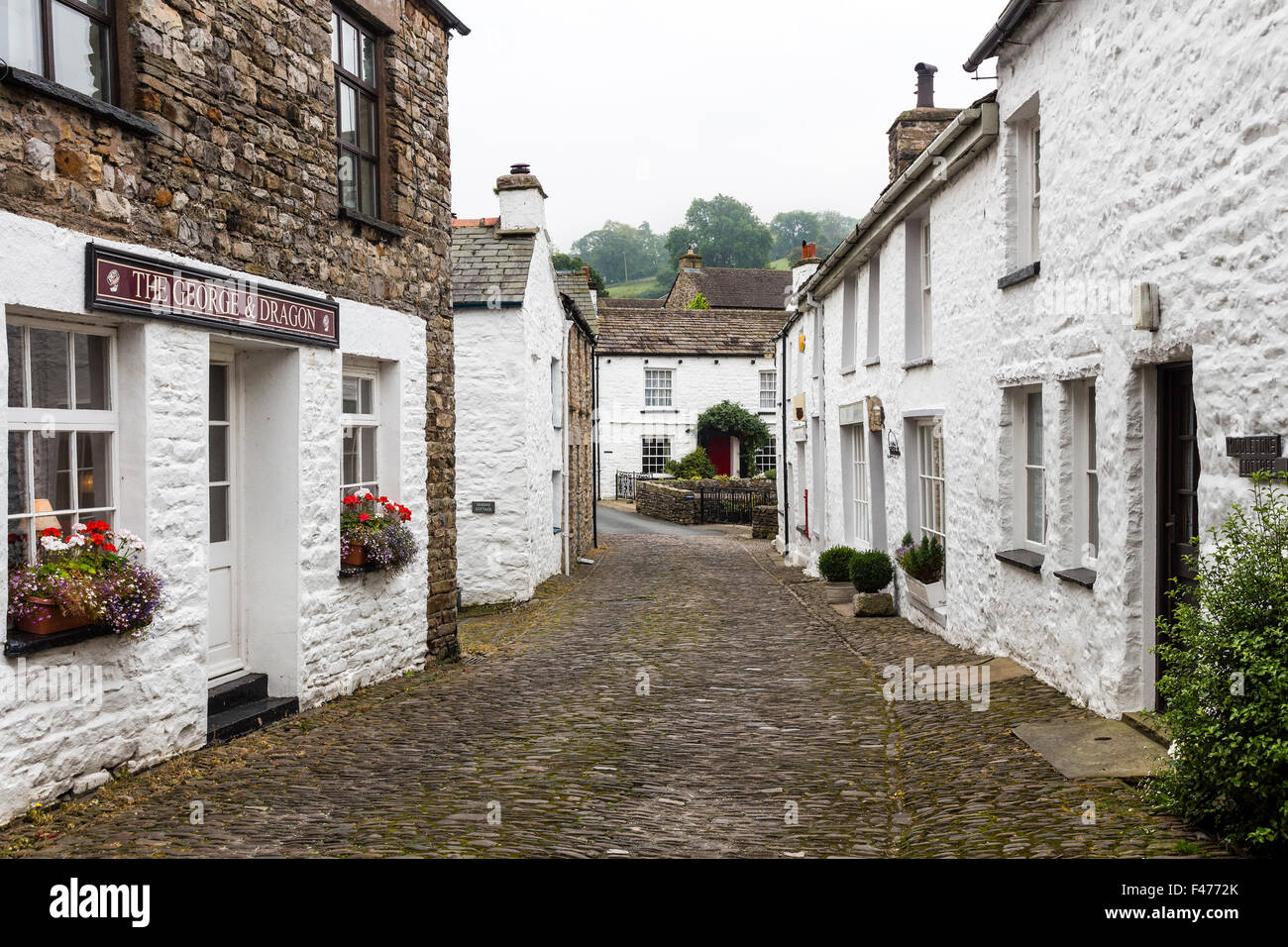 Case imbiancate a calce e strada di ciottoli nel villaggio di ammaccatura, Dentdale, Cumbria, Regno Unito Foto Stock