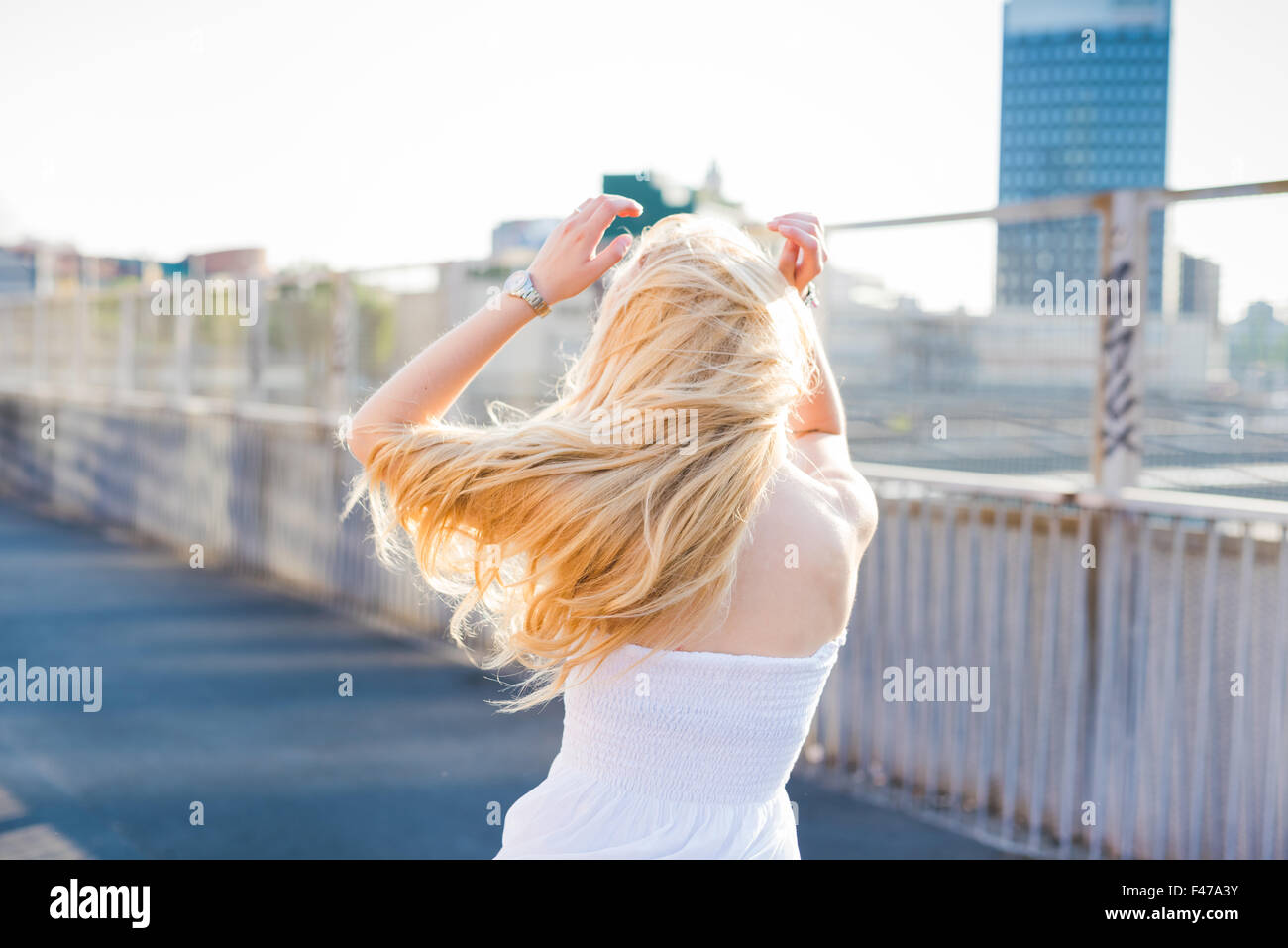 Giovani caucasici belli lunghi biondi capelli dritti woman dancing in città, vista dal retro, sentendosi liberi nella città - il ballo, la libertà, il concetto della gioventù Foto Stock