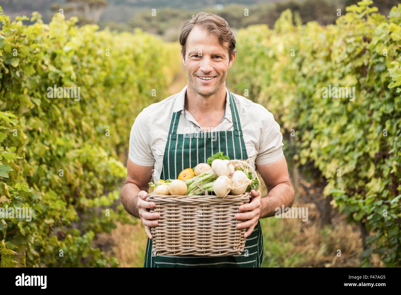 Sorridendo l'agricoltore che detiene un cesto di verdure Foto Stock