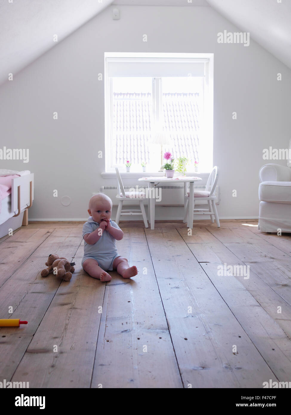 Baby ragazza seduta sul pavimento di legno, Svezia. Foto Stock