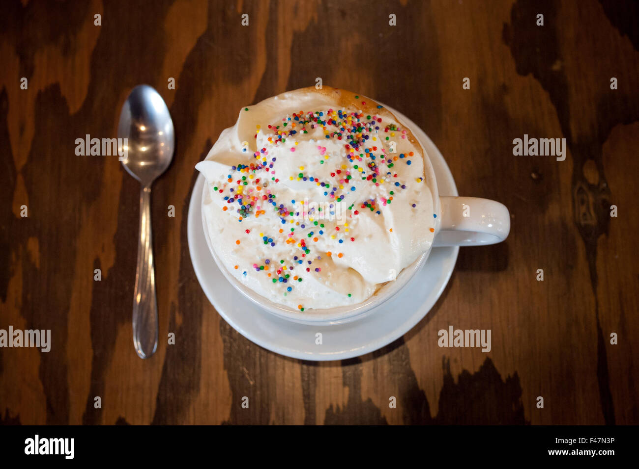 Un caldo Torta di compleanno latté con granelli colorati e panna montata dal d'Lish da Tish Café di Saskatoon, Saskatchewan, Canada. Foto Stock