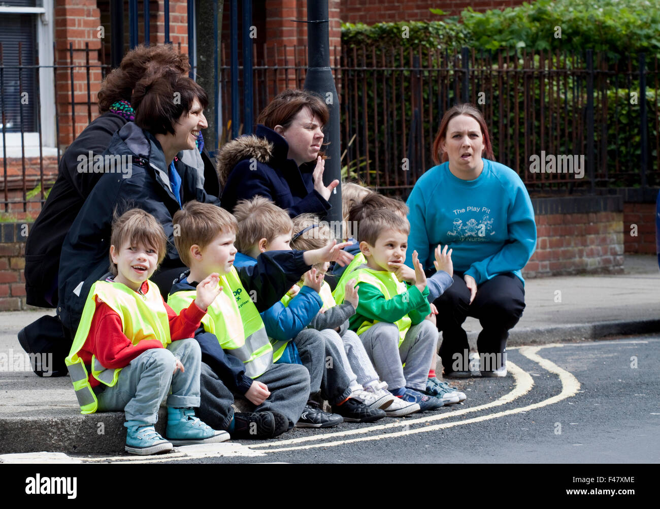 Bambini piccoli sedersi su un cordolo in attesa per il 2014 donne's Tour della Gran Bretagna per passare Foto Stock