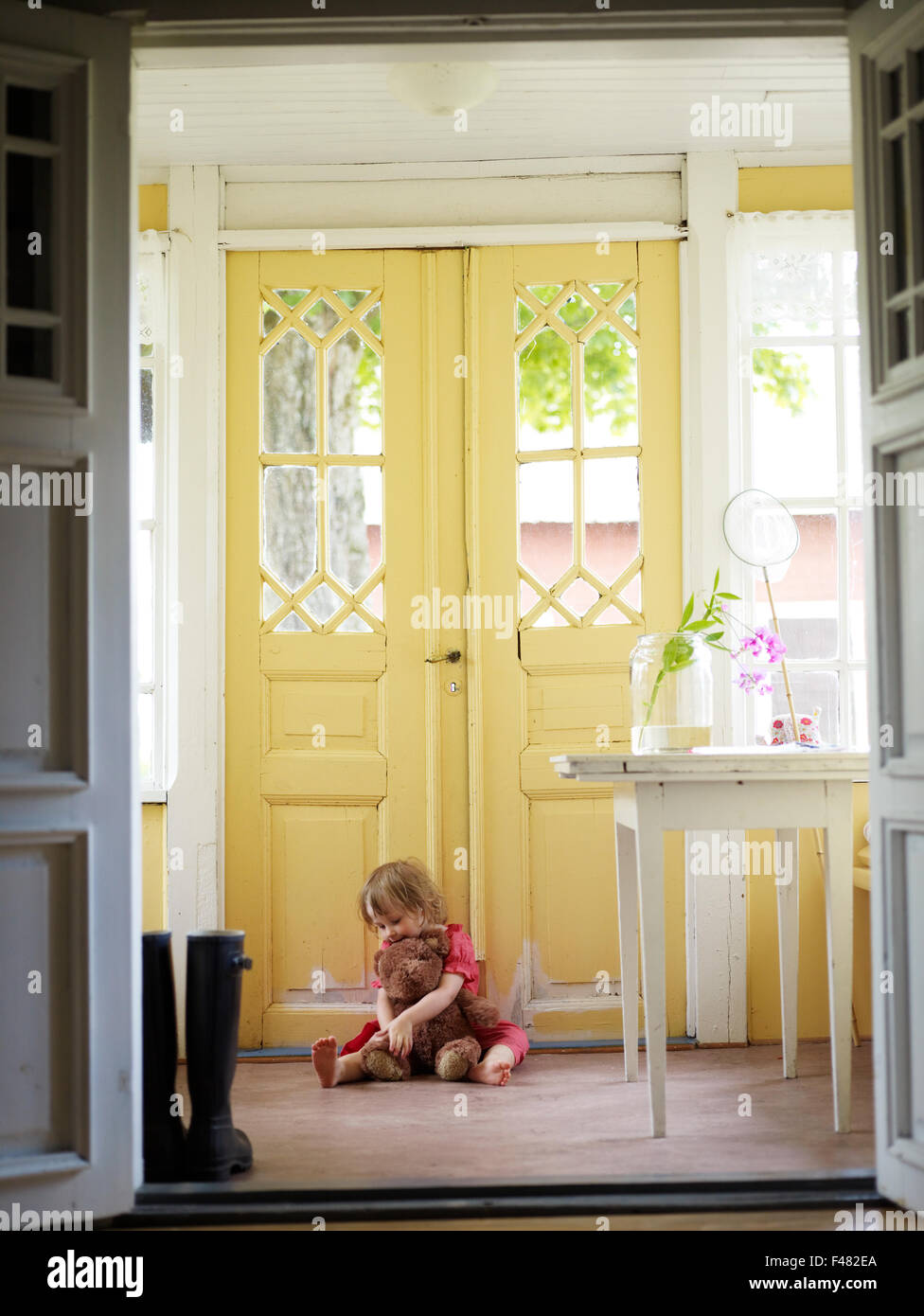 Ragazza con un orsacchiotto da una porta esterna, Svezia. Foto Stock