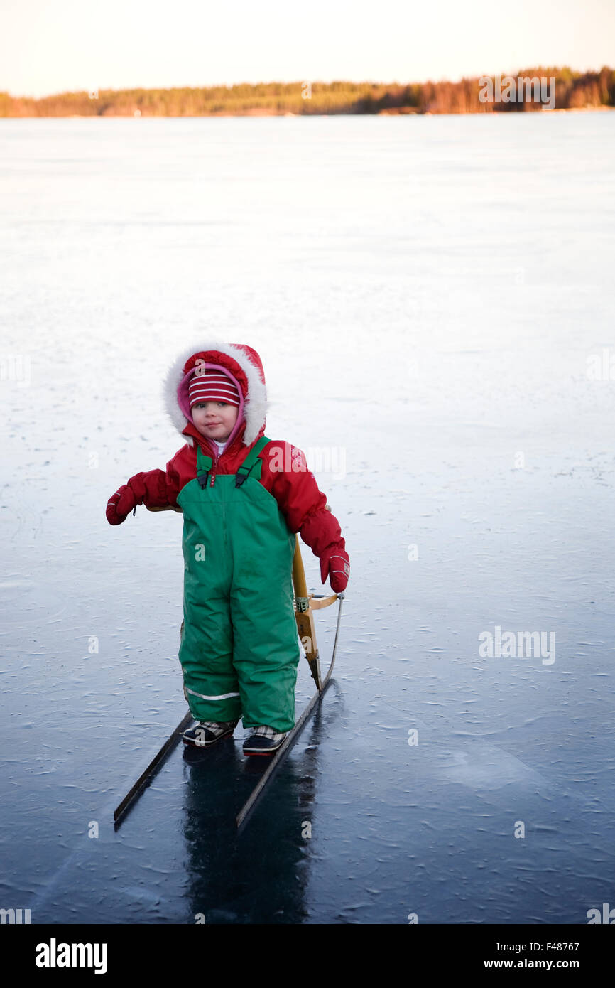 Una piccola ragazza da un kick-sled su un lago ghiacciato, Svezia. Foto Stock
