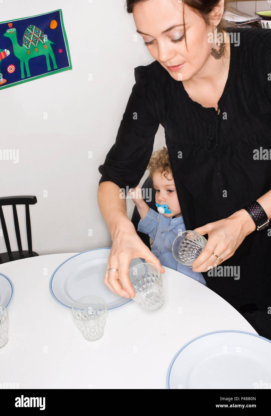 Una madre impostando il tavolo per la cena da suo figlio, Svezia. Foto Stock