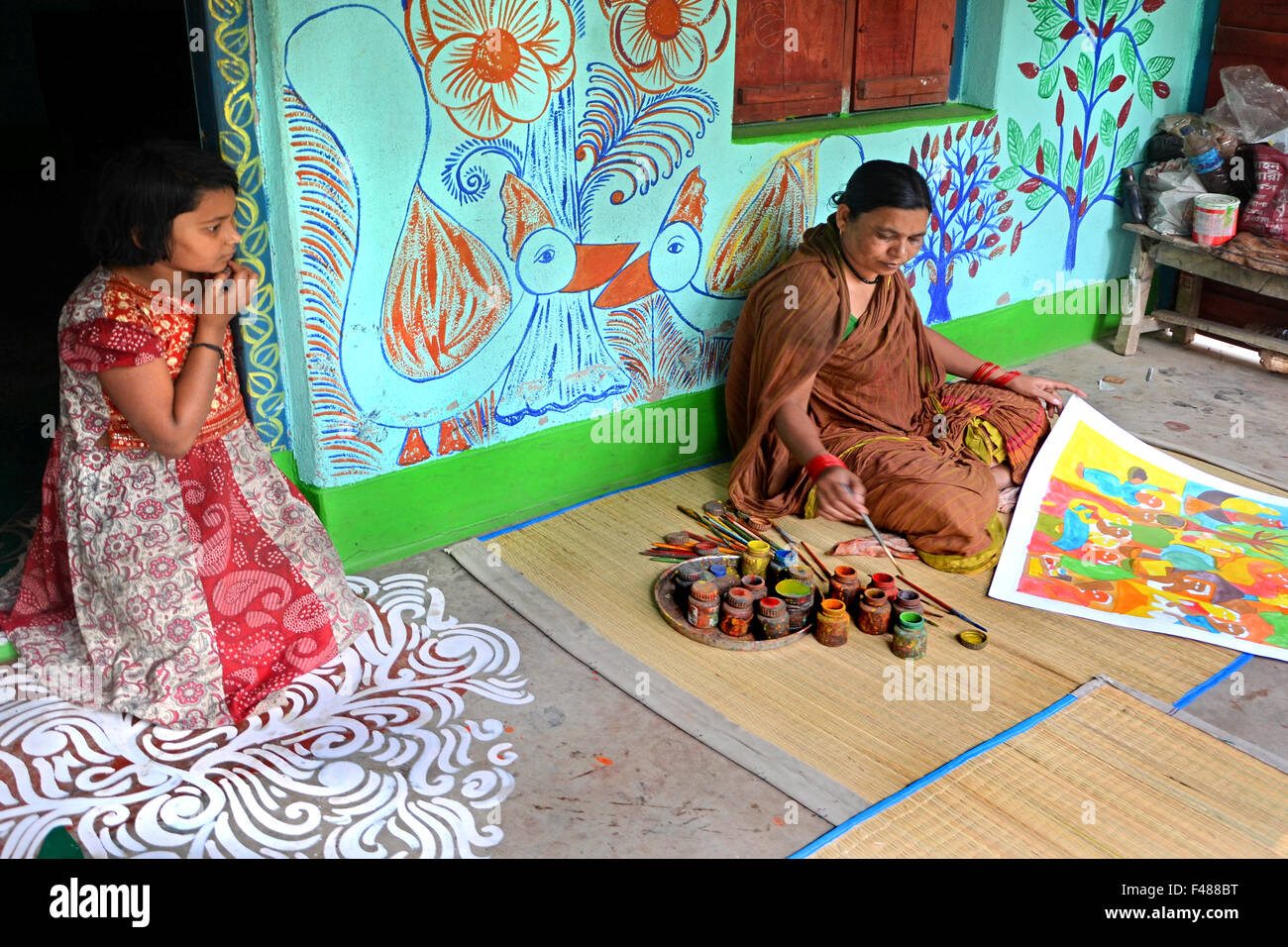 Studente - Una donna indiana di disegno tradizionale pittura davanti a casa sua. Ella disegno molte cose su carta o su tela. Foto Stock