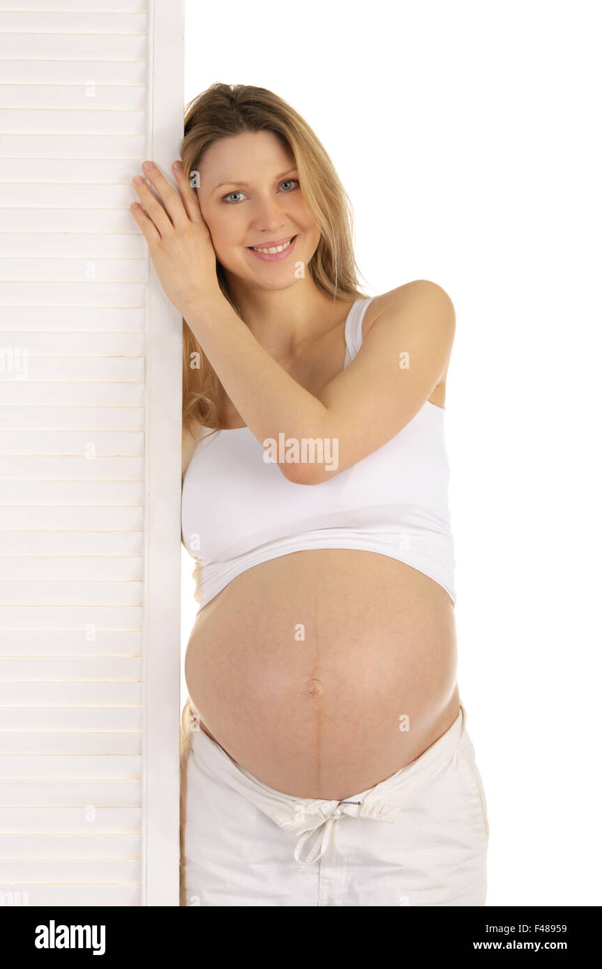 Felice donna incinta in piedi vicino alla porta Foto Stock