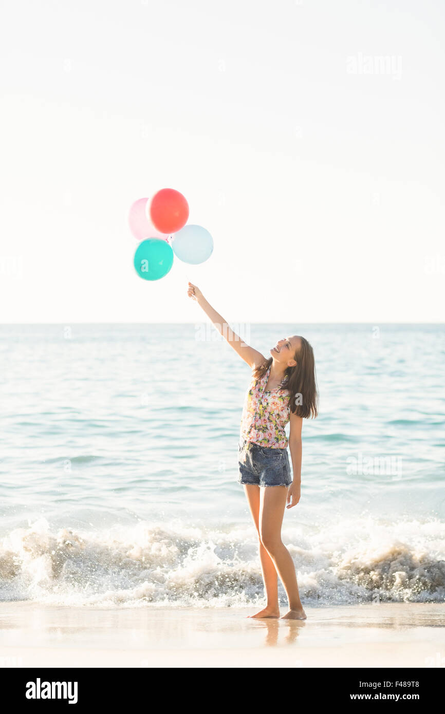 Felice ragazza che gioca sulla sabbia con palloncino Foto Stock