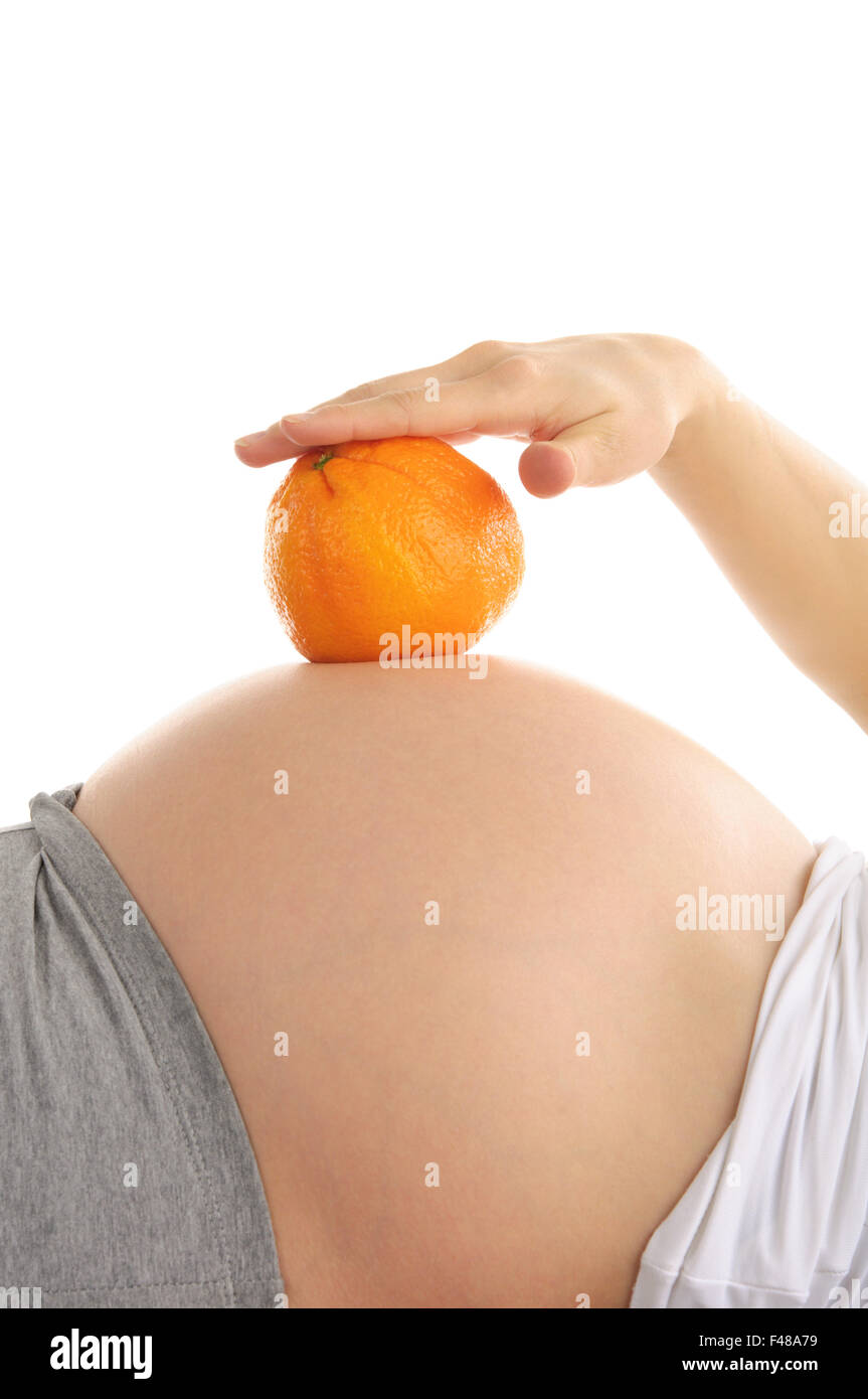 Della donna incinta, addome con arancia Foto Stock