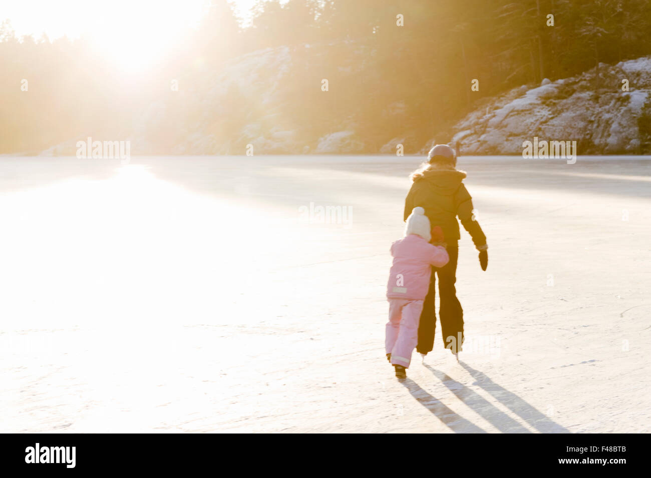 Sorelle pattinaggio contro la luce, Svezia. Foto Stock