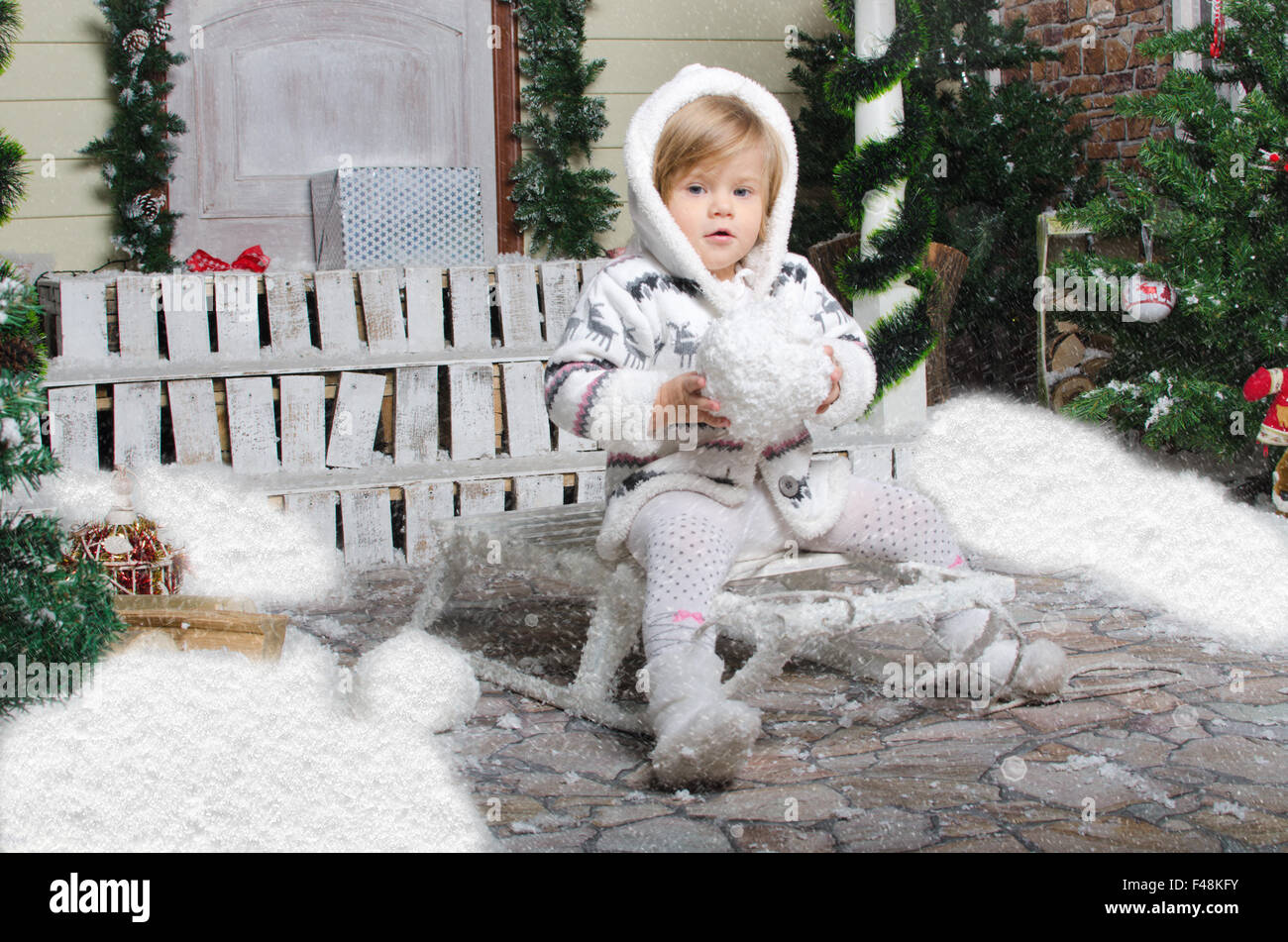 Il bambino si siede sulla slitta con la neve in mani Foto Stock