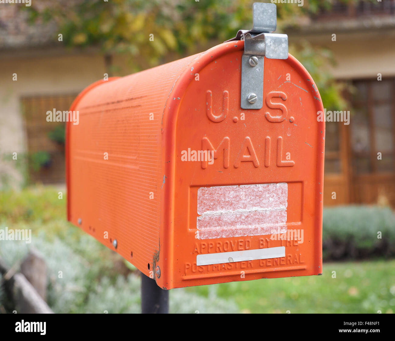 In prossimità di una vecchia casa letter box, verniciato di colore arancione, con lo sfondo della casa rurale. Foto Stock