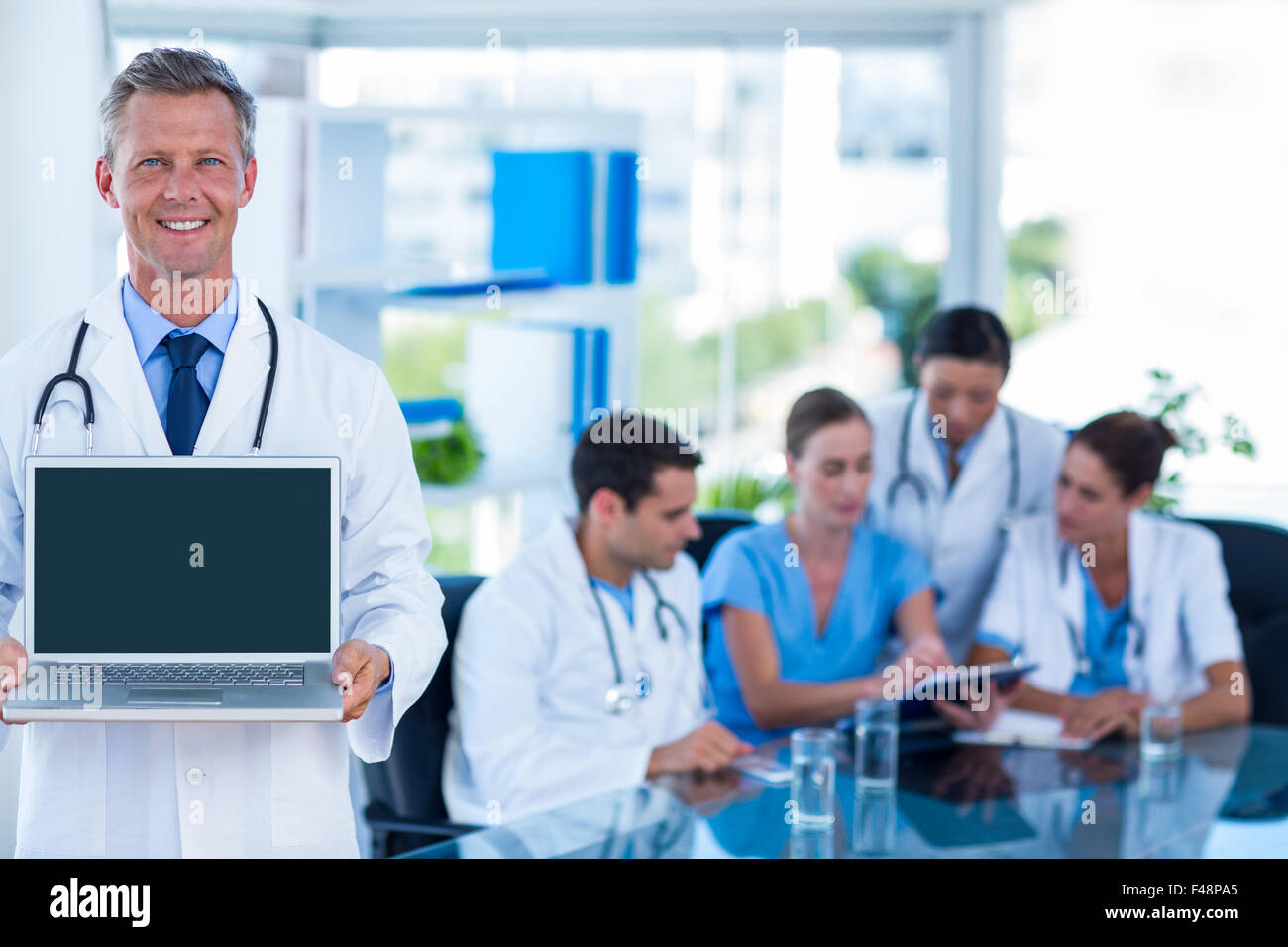 Medico mostra portatile con i colleghi dietro Foto Stock