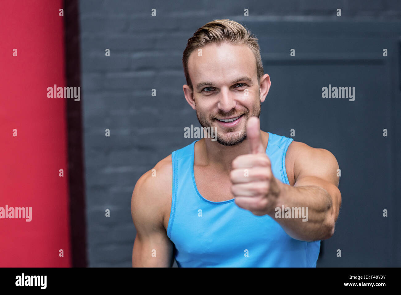 Uomo muscolare gesticolando pollice in alto Foto Stock