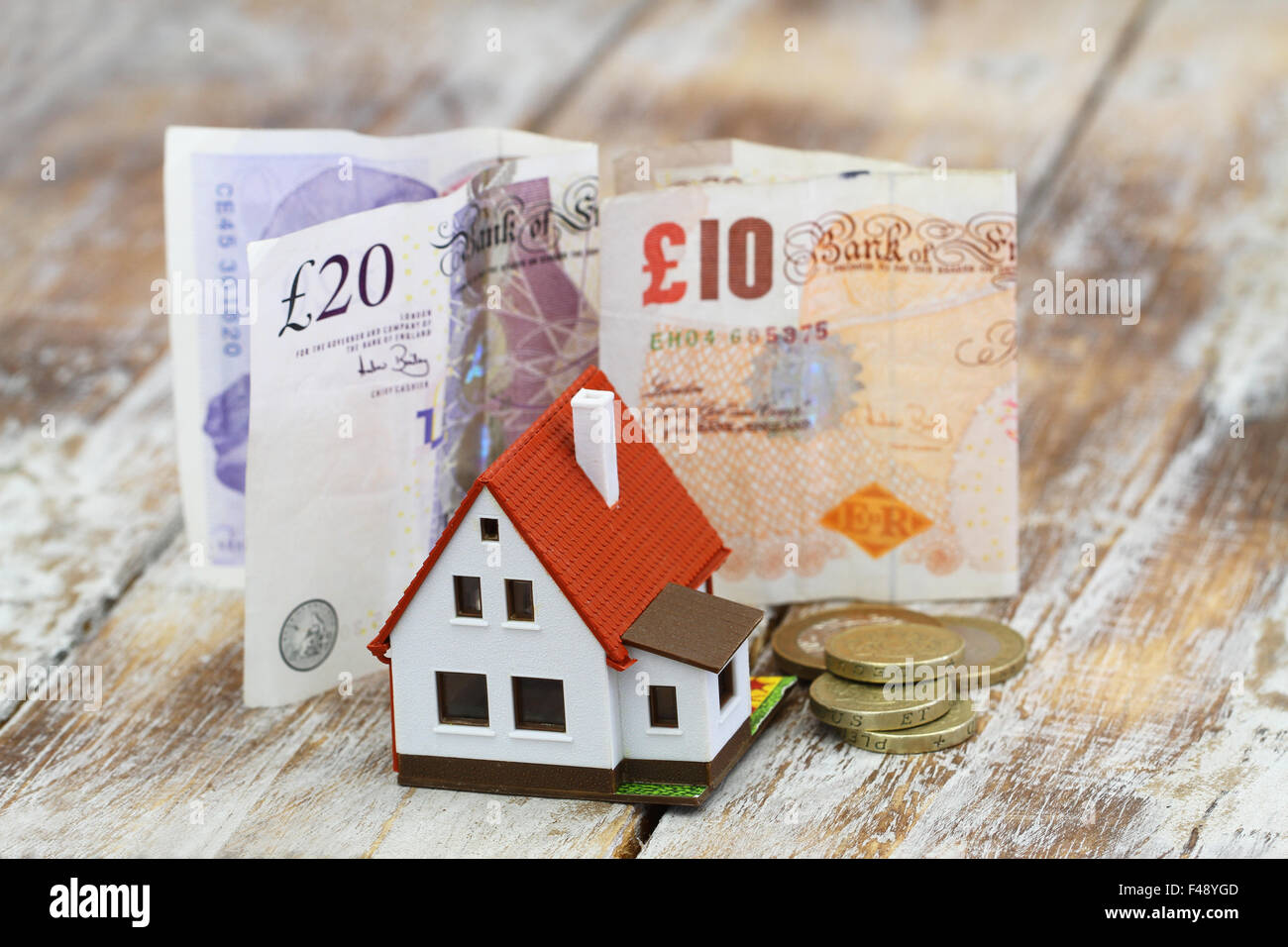 Modello di casa nella parte anteriore del British pound banconote e monete Foto Stock