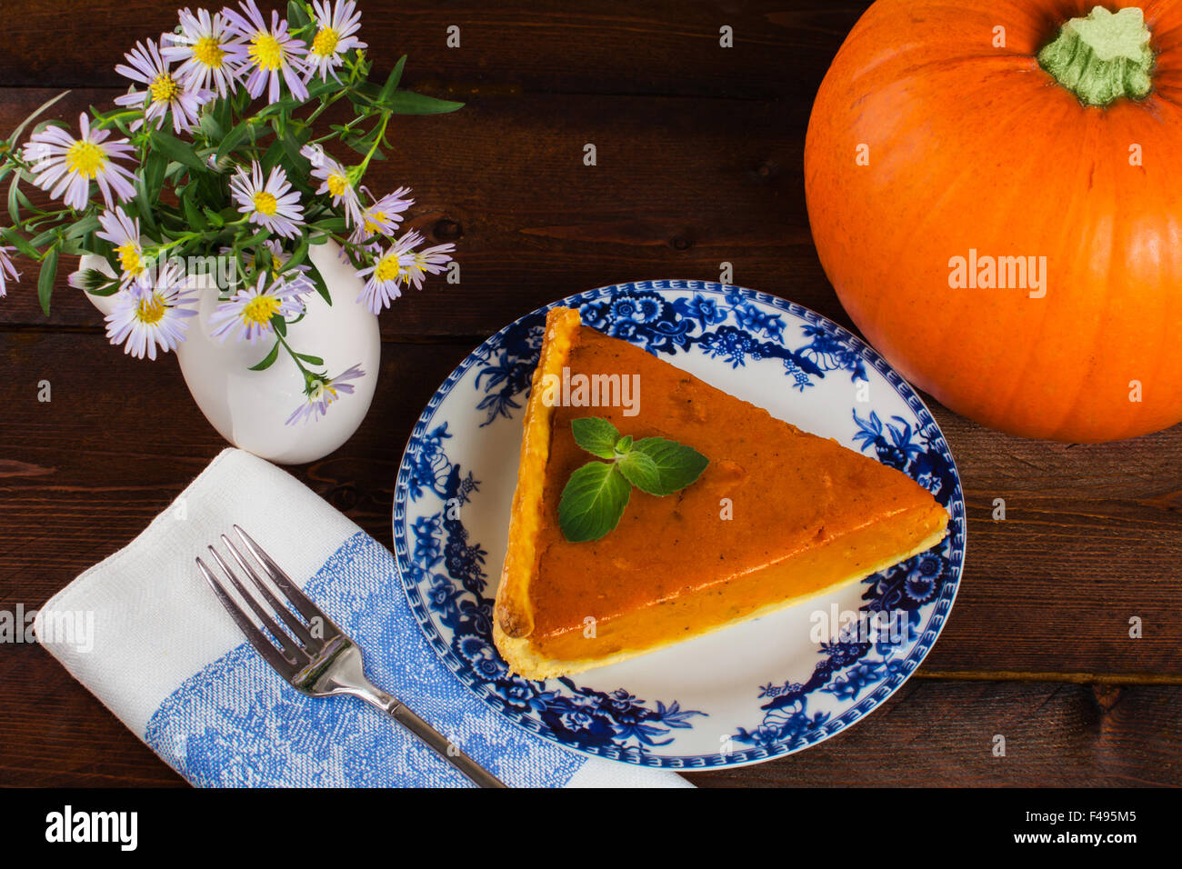 Ringraziamento zucca fetta di torta sulla piastra, biancheria igienico, un vaso di fiori lilla su uno sfondo di legno Foto Stock