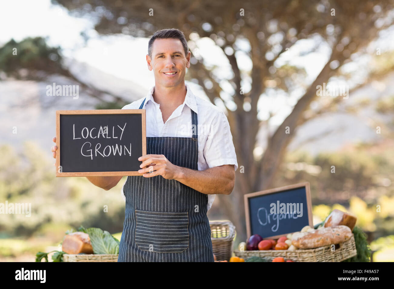 Sorridendo l'agricoltore che detiene un coltivato localmente segno Foto Stock