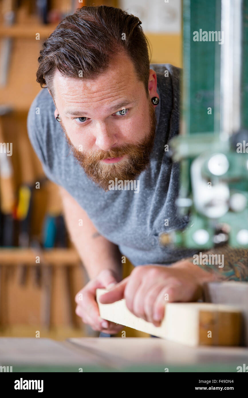 Artigiano utilizzando segatrice a nastro per il legno divisione listone in officina Foto Stock
