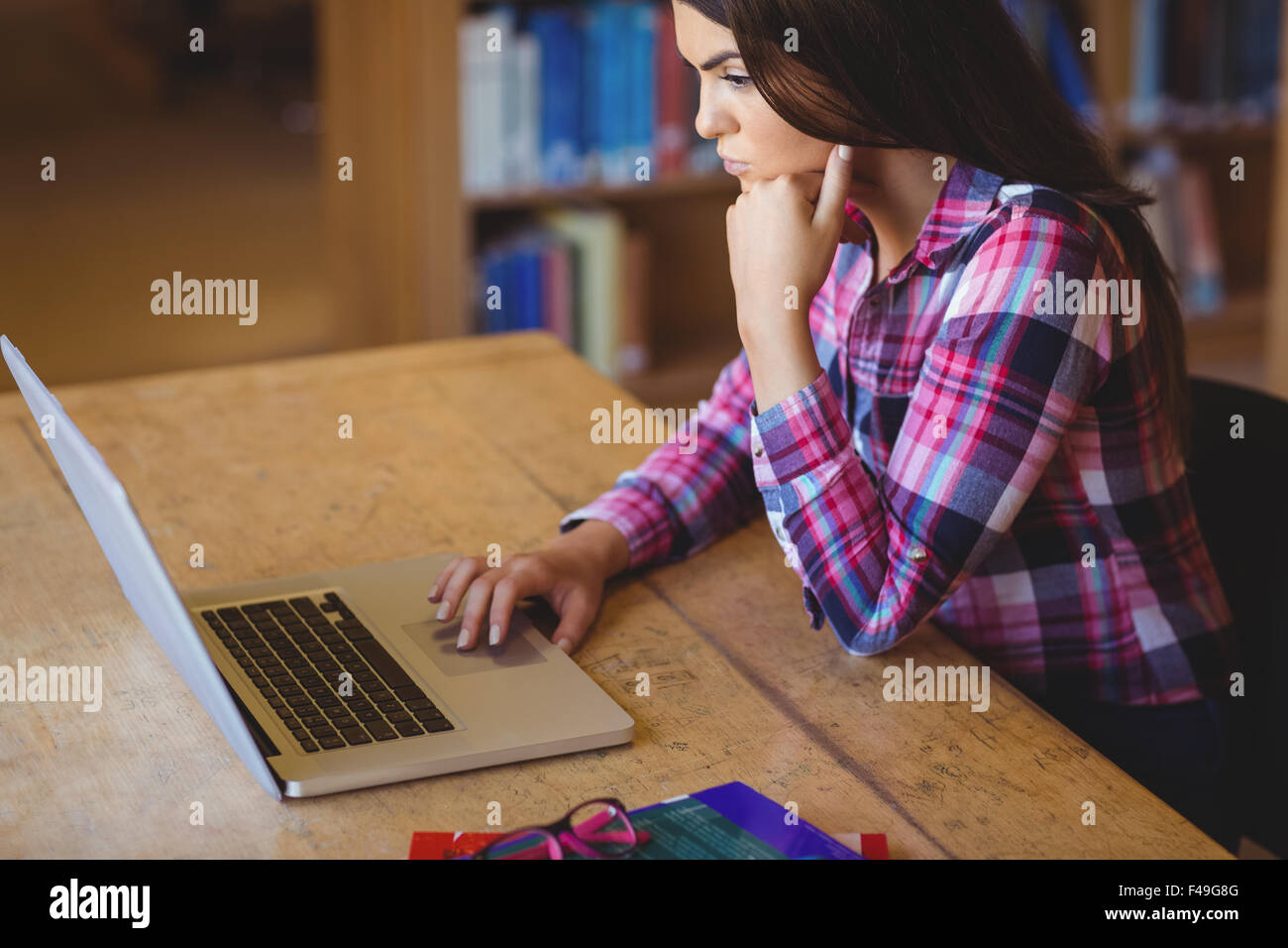Femmina concentrato studente utilizzando laptop in biblioteca Foto Stock
