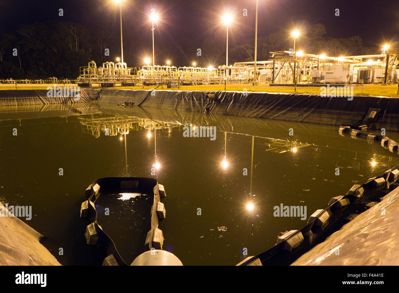 Serbatoio di acqua di produzione su un pozzo di petrolio piattaforma nell'Amazzonia ecuadoriana, illuminata di notte Foto Stock