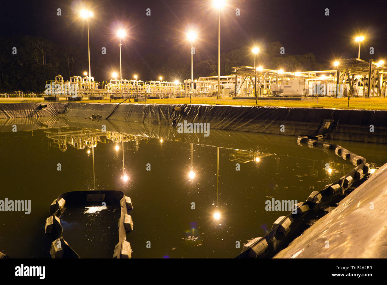 Serbatoio di acqua di produzione su un pozzo di petrolio piattaforma nell'Amazzonia ecuadoriana, illuminata di notte Foto Stock
