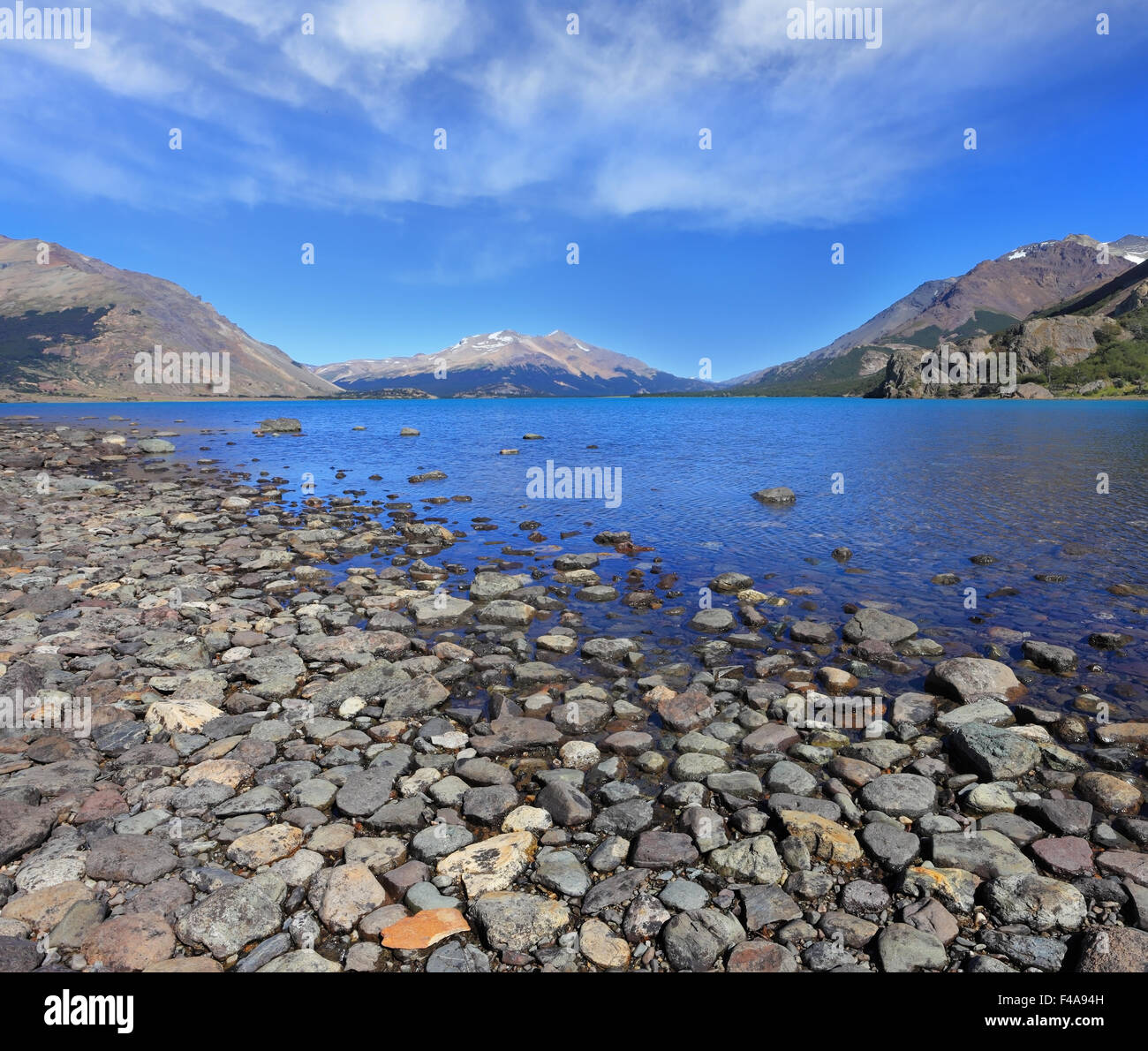 Lago blu con una spiaggia rocciosa Foto Stock