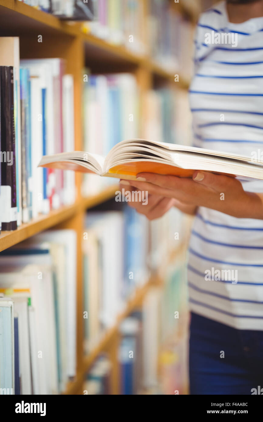 Donna con libro in biblioteca Foto Stock