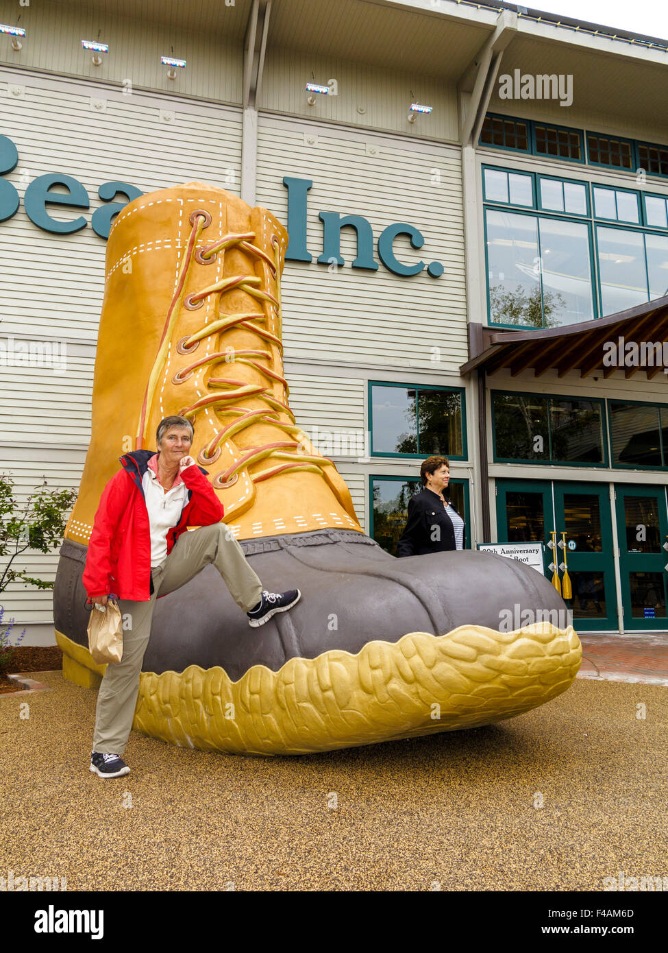 Donna appoggiata su un enorme L.L. Bean iconico boot al di fuori del loro negozio in Freeport, Maine Foto Stock