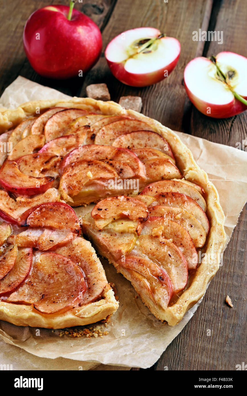 La frutta la torta di mele su carta da forno sul tavolo rustico Foto Stock