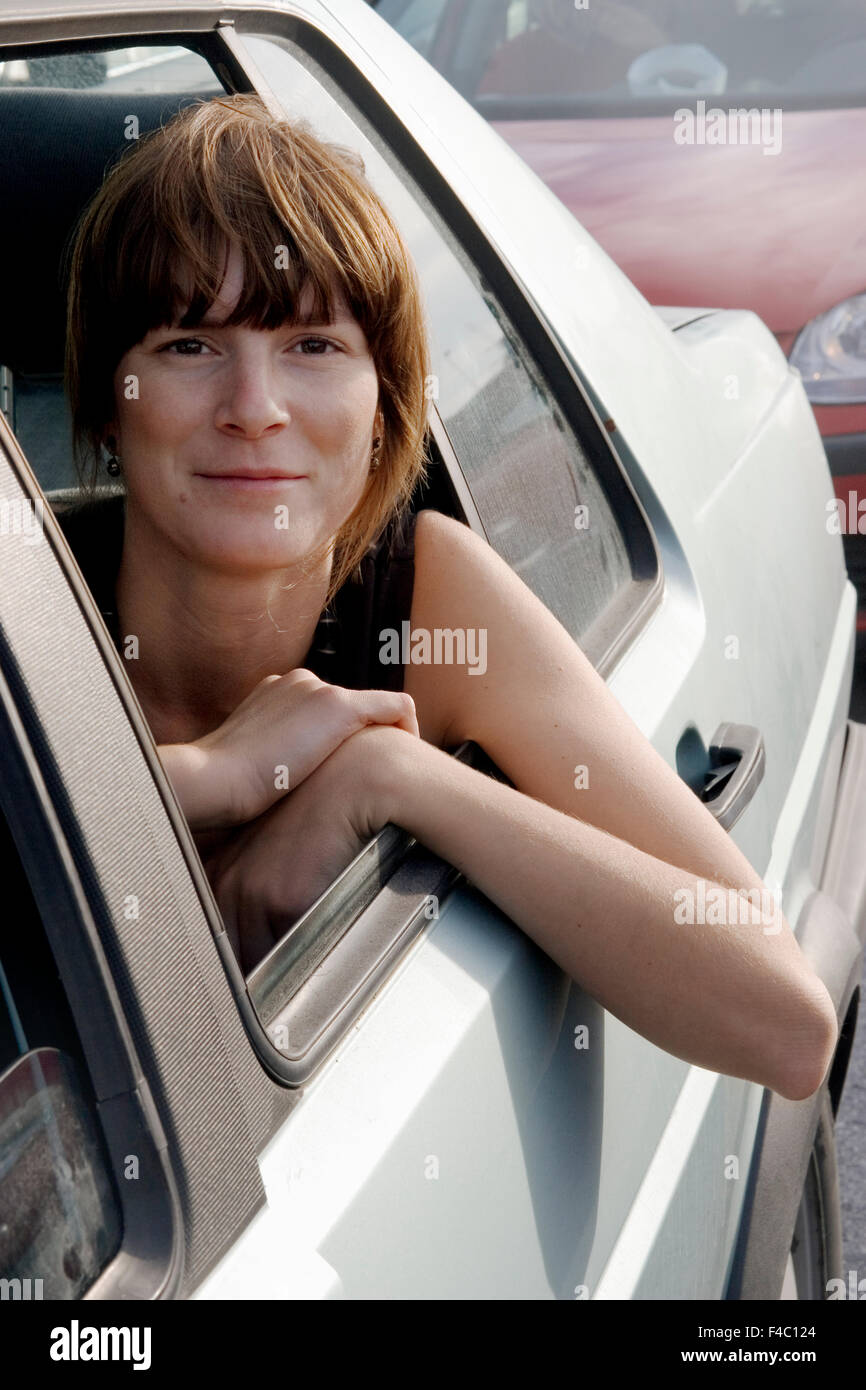 Una donna che guarda fuori attraverso il finestrino di un'automobile. Foto Stock