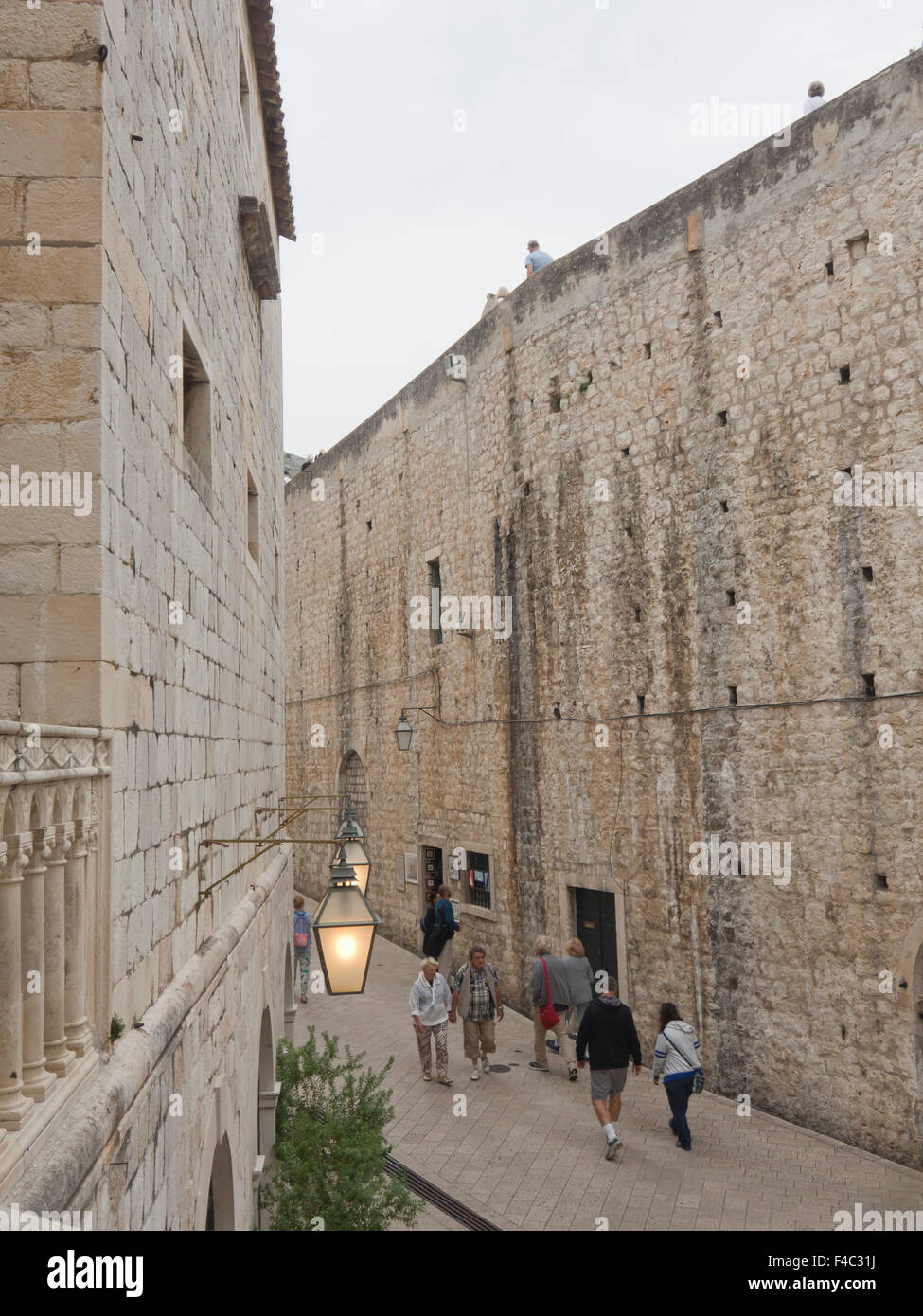 I turisti a camminare in una strada stretta lungo le mura di fortificazione nella città vecchia 'Stari Grad' in Dubrovnik Croazia Foto Stock
