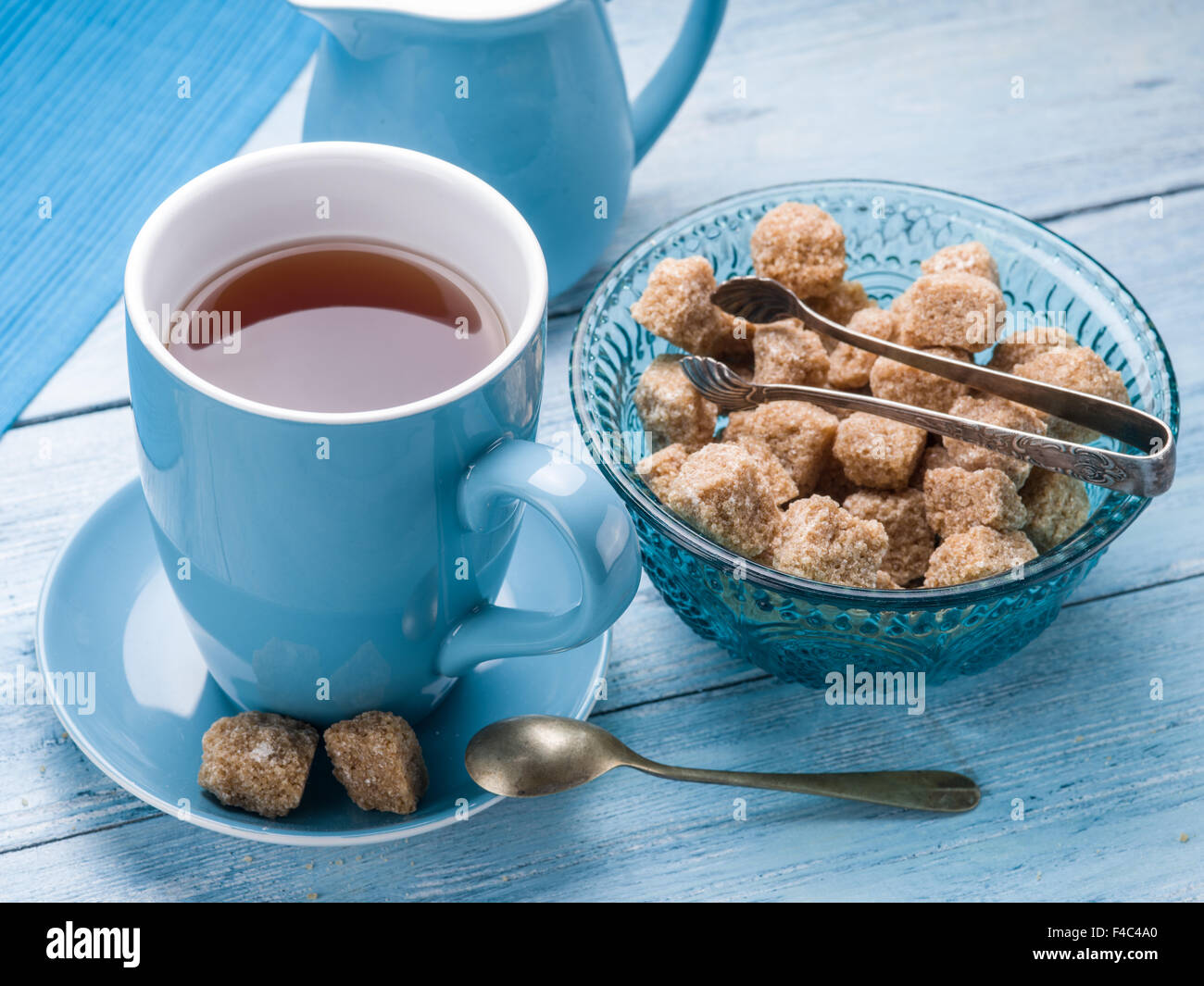 Zucchero di canna cubi nella vecchia lastra di vetro blu su un tavolo di legno. Foto Stock
