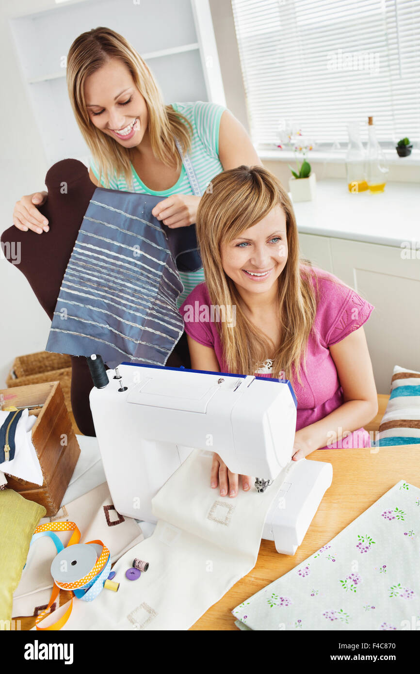 Felice giovani amici femminili abiti da cucire insieme a casa Foto Stock